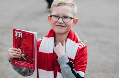 Kid with a football matchday programme